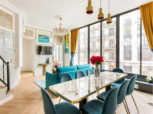 une salle à manger avec une table en verre et des chaises bleues dans l'établissement Merveil - Luxury Suite - Louvre - Reaumur II, à Paris