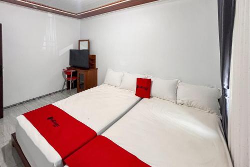 a white and red bed in a room with a television at RedDoorz at Mbak Tinem Near Bandara Lubuk Linggau in Tabahpingin