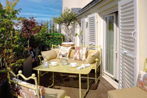 d'une terrasse avec une table et un canapé sur un balcon. dans l'établissement Ultra luxe et Confort au Coeur des champs-Elysees, à Paris