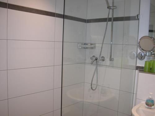 a shower with a glass door next to a sink at Hotel-Restaurant Zum Hirschhaus Inklusiv Chiemgaukarte in Ruhpolding