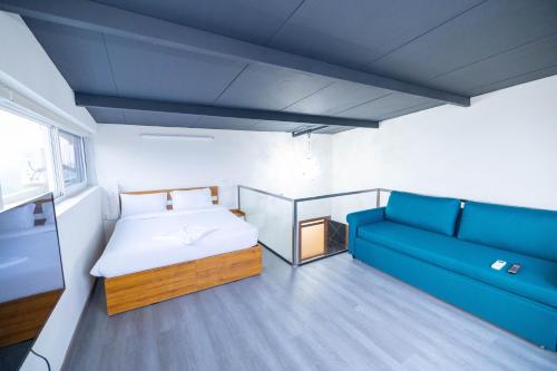 a bedroom with a bed and a blue couch at Solandis Service Apartment in Manipala