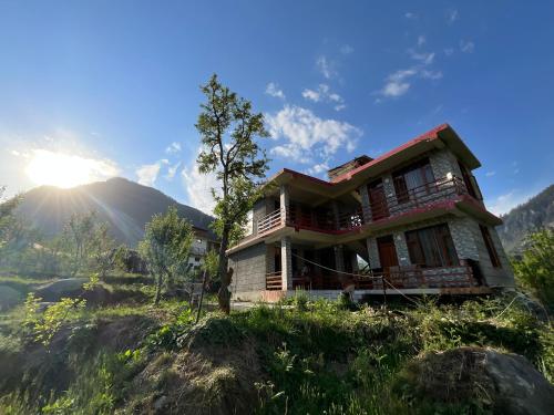 a house on a hill with the sun in the background at By The Way in Manāli