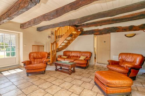a living room with leather furniture and a staircase at Maison avec grand jardin 10km plage in Férel