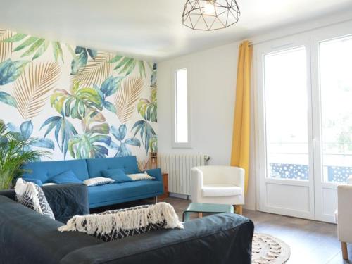 - un salon avec un canapé bleu et du papier peint tropical dans l'établissement Maison RAVI, à Lectoure
