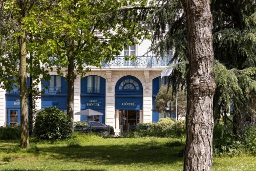 a blue and white building with trees in the foreground at Le Plessis Grand Hotel in Le Plessis-Robinson