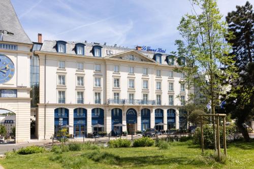 a large white building with a clock on it at Le Plessis Grand Hotel in Le Plessis-Robinson