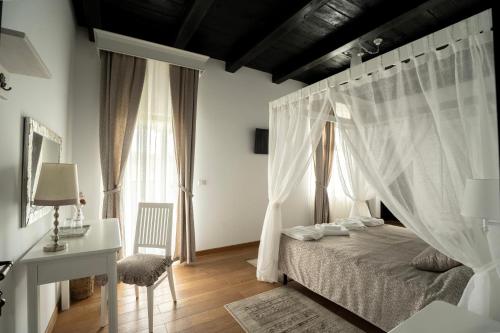 a bedroom with a bed with white curtains and a desk at Pensiunea Cocosel in Căstău