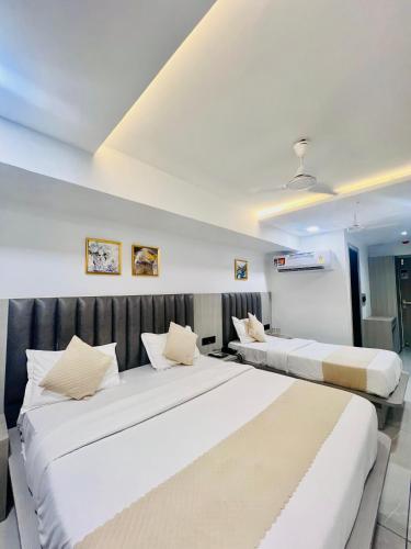 two beds in a hotel room with white walls at Hotel Metro Inn in Ahmedabad