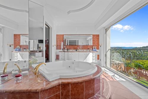 une grande salle de bain avec une baignoire et une grande fenêtre dans l'établissement Prestigious Villa in Mougins 6 bedrooms spa cinema and nightclub, à Mougins