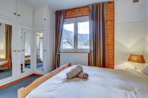 a bedroom with a large white bed and a window at Self Catered Chalet with Indoor Pool in Essert-Romand