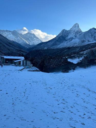 a snow covered field with mountains in the background at The Himalayan Tyangboche in Lukla