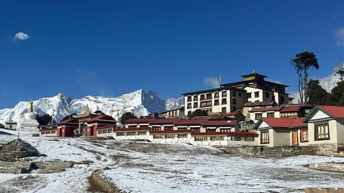 a group of buildings with snowy mountains in the background at The Himalayan Tyangboche in Lukla
