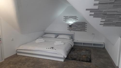 a white bedroom with a bed with a light above it at Guesthouse Next to beach in Batumi