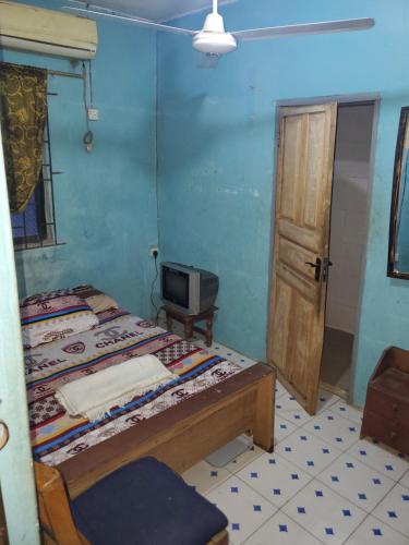 a room with two beds and a tv and a door at Top Guest Room in Ikorodu