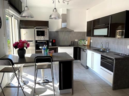 une cuisine avec des appareils en noir et blanc et une table dans l'établissement Les 3 Cépages - Gîte, à Épernay