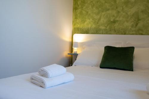 two towels on a bed with a green pillow at Baglio dei Mori in Donnalucata