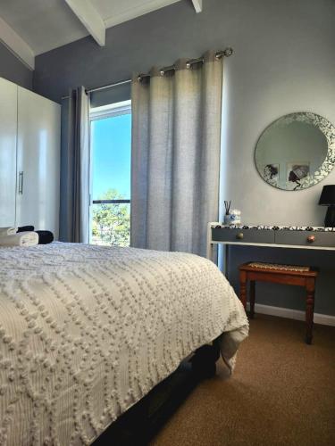 a bedroom with a bed and a mirror and a window at Knoll at Oaklands - Two Bedroom APT Knysna Retreat! in Knysna