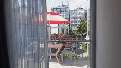 a table with a red umbrella on a balcony at Guesthouse Next to beach in Batumi