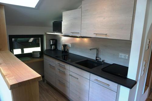 a kitchen with a sink and wooden cabinets at Der Sonnenhof - Ferienwohnungen in Obermaiselstein