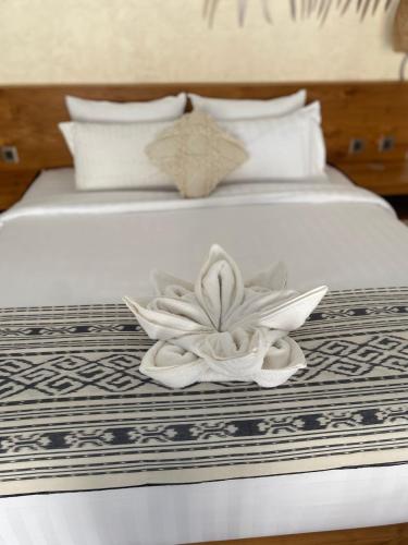a bed with two white towels and a flower on it at Santai Suites Nusa Dua in Nusa Dua