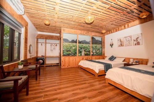 a bedroom with two beds and a table and windows at Hang Mua Luxury Homestay in Xuân Sơn