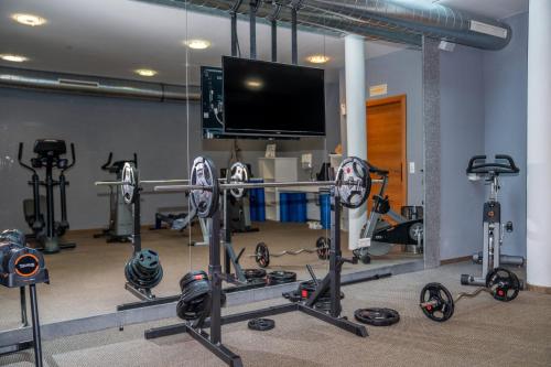 a gym with several bikes and a flat screen tv at Hotel Andy 4 Sterne Superior in Jerzens