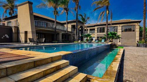 a swimming pool in front of a house with palm trees at Ondjo Yetu in Benoni