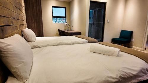 a hotel room with three beds and a chair at Ondjo Yetu in Benoni