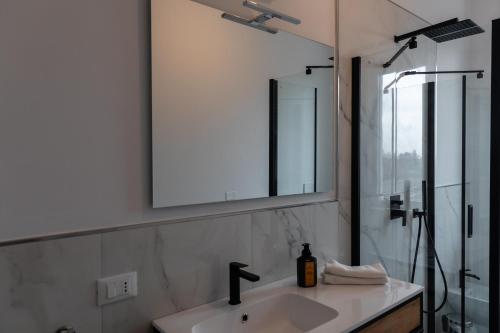 a bathroom with a sink and a mirror and a shower at Elegant Apartment Biella, near Hospital ! in Gaglianico