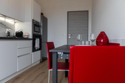 a kitchen with a black table and red chairs at Elegant Apartment Biella, near Hospital ! in Gaglianico