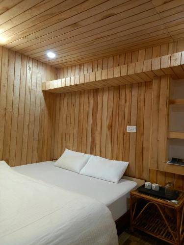 a bedroom with a bed and a wooden wall at Hotel Himalayan in Madheso