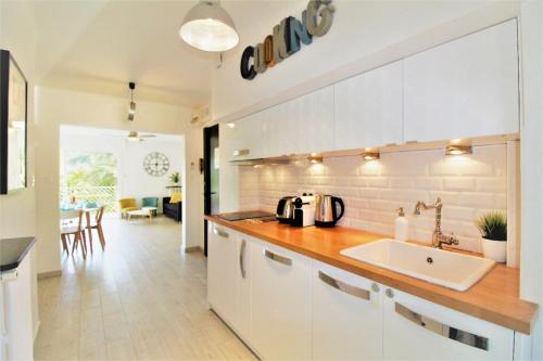 une cuisine blanche avec un évier et un comptoir dans l'établissement La Cigale Sanaryenne et son Jardin Méditerranéen, à Sanary-sur-Mer