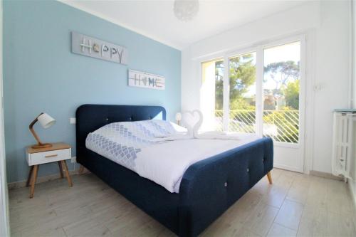 une chambre bleue avec un lit et une fenêtre dans l'établissement La Cigale Sanaryenne et son Jardin Méditerranéen, à Sanary-sur-Mer