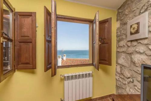 a bathroom with a window with a view of the ocean at La casina del Penayu in Lastres