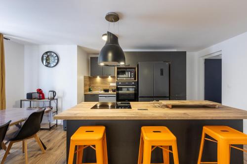 une cuisine avec un grand îlot avec des tabourets orange dans l'établissement Le Bol d'Err - Vue Montagne, à Err