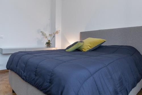 a bed with a blue comforter and a yellow pillow at Elegant Apartment Biella, near Hospital ! in Gaglianico