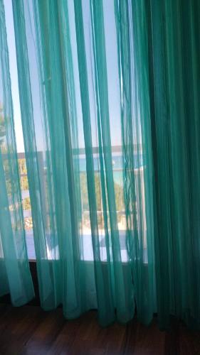 a window with green curtains in a room at Fronte mare rooms in Palermo