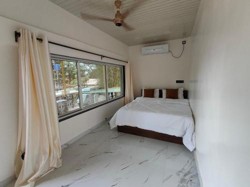 a bedroom with a bed and a large window at Radiant villa in Panchgani