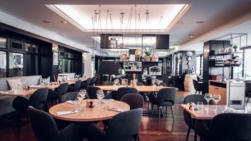 a restaurant with wooden tables and chairs and a kitchen at Holiday Inn Mulhouse by IHG in Mulhouse