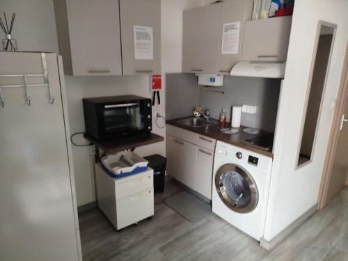 une cuisine avec un lave-linge et un micro-ondes dans l'établissement Appartement vacances cap d’agde, au Cap d'Agde