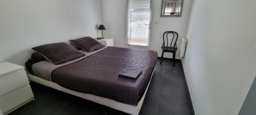 une chambre avec un lit, une chaise et une fenêtre dans l'établissement bee free, à Montalivet-les-Bains