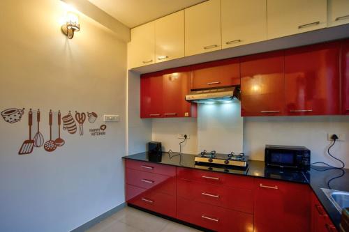 a kitchen with red cabinets and a counter top at Coastal Bliss By Masaka in Anjuna