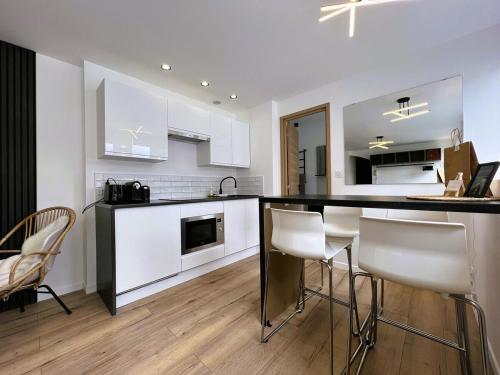une cuisine avec des placards blancs et un bar avec des chaises dans l'établissement Suite Aube-Studio 2 pers lumineux centre ville, à Charleville-Mézières