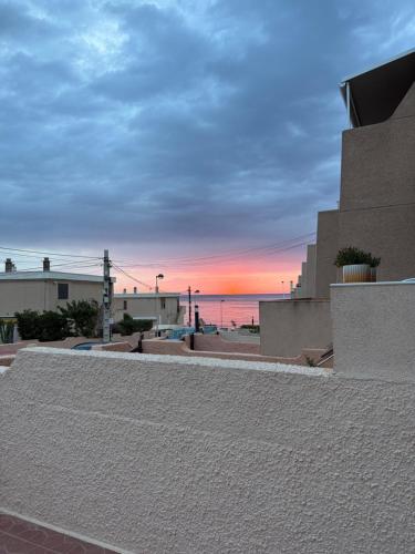 einen Sonnenuntergang über dem Meer von einem Gebäude in der Unterkunft Adosado playa de la Mata con vistas al mar in Torrevieja