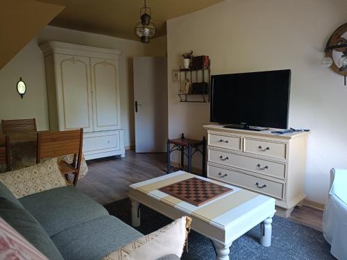 a living room with a couch and a tv on a dresser at Maison dans un environnement boisé très calme in Morlaix