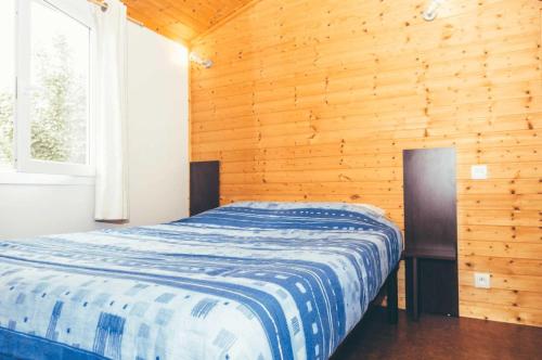 une chambre avec un lit dans une pièce en bois dans l'établissement Chalet 3 étoiles - Piscine - eebbhg, à Beynat