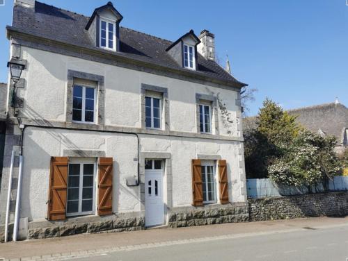 an old white house with brown doors and windows at L'Astu'Cieux appartement triplex in Huelgoat