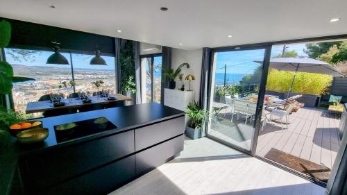 une cuisine avec un comptoir noir et une vue sur un patio dans l'établissement VILLA ROUQUIER, Vue Panoramique, Mer et Port de Sète, Climatisé, Jacuzzi, à Sète