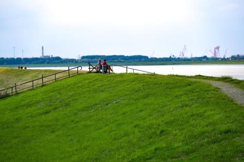 two people sitting on a grassy hill next to a body of water at Ferienwohnung Siel 40 Ditzum 45253 in Ditzum