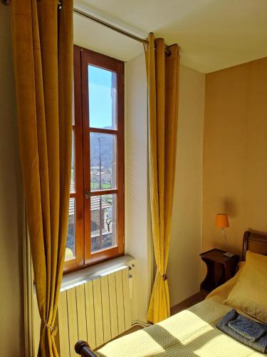 une chambre avec un lit et une fenêtre avec des rideaux dans l'établissement Les Chambres de la Violette, à Grenier-Montgon